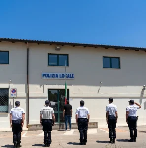Foto dei vigili della Polizia Locale di Monteroni di Lecce di fronte alla sede con bandiera a mezz'asta